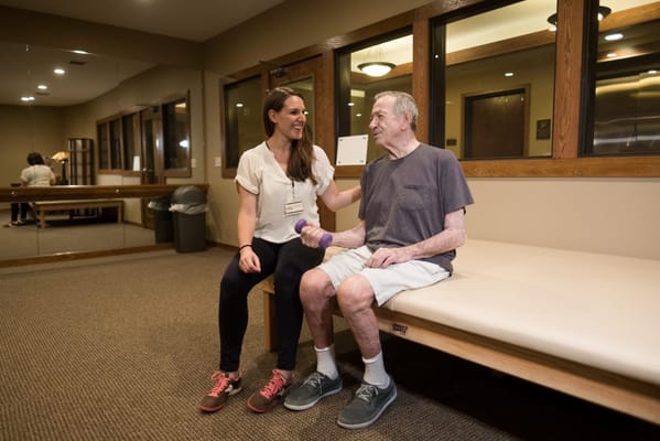 Staff assisting a resident with exercise in a fitness room