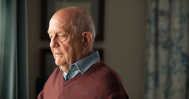 An elderly man in a contemplative moment indoors