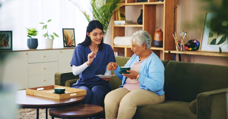 Staff assisting a resident with a meal on a sofa