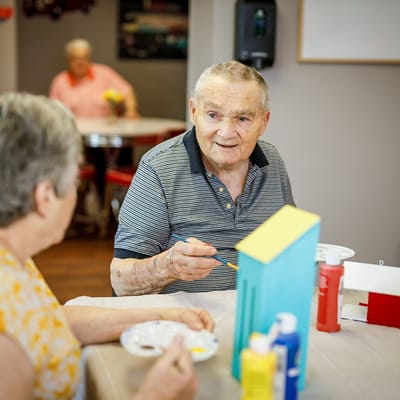 Residents engaging in a painting activity in an activity room