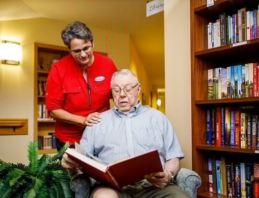 Staff member assisting a resident in a library area