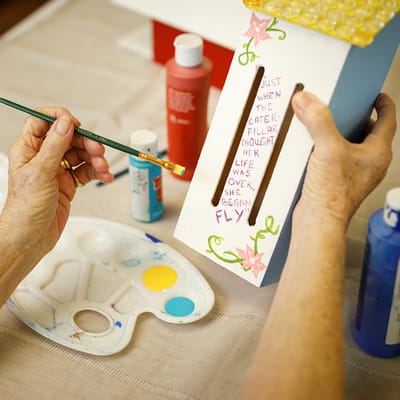 A resident painting a decorative birdhouse with vibrant colors