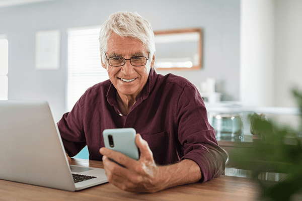 Senior man using a smartphone while sitting at a desk