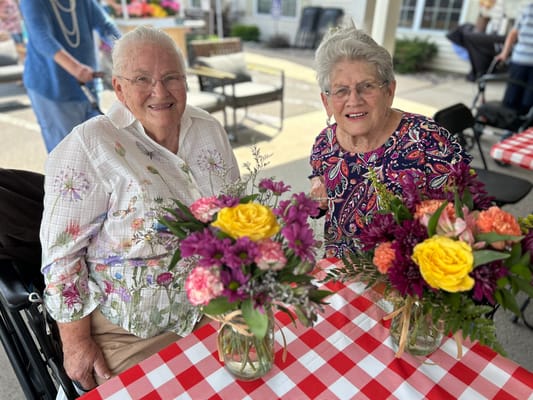 Two residents enjoying flowers at a table outdoors