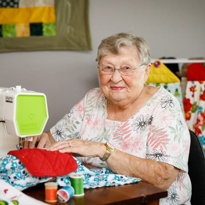 Resident sewing a quilt in a cozy environment
