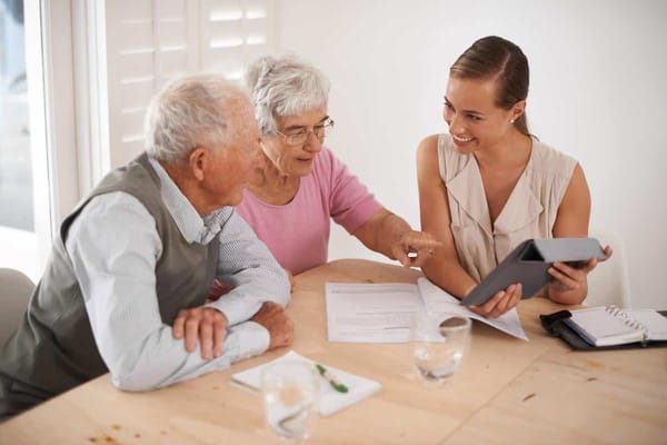Staff member assisting elderly residents with a tablet
