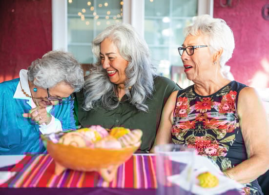 Three women enjoying dessert in a vibrant common area