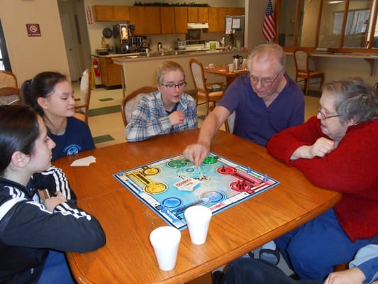 Residents and volunteers playing a board game at a table