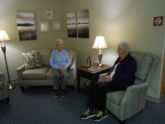 Two residents seated in a common area with lamps