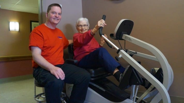 Staff member assisting a resident with exercise equipment