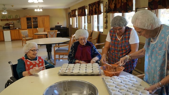 Residents and staff preparing cupcakes in an activity room