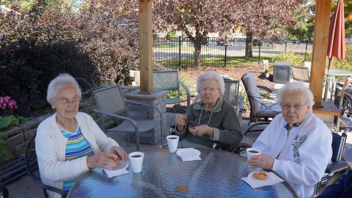 Three residents enjoying coffee and cookies outdoors