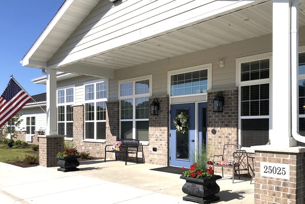 Front entrance of Archwood Senior Living with flowers and flag