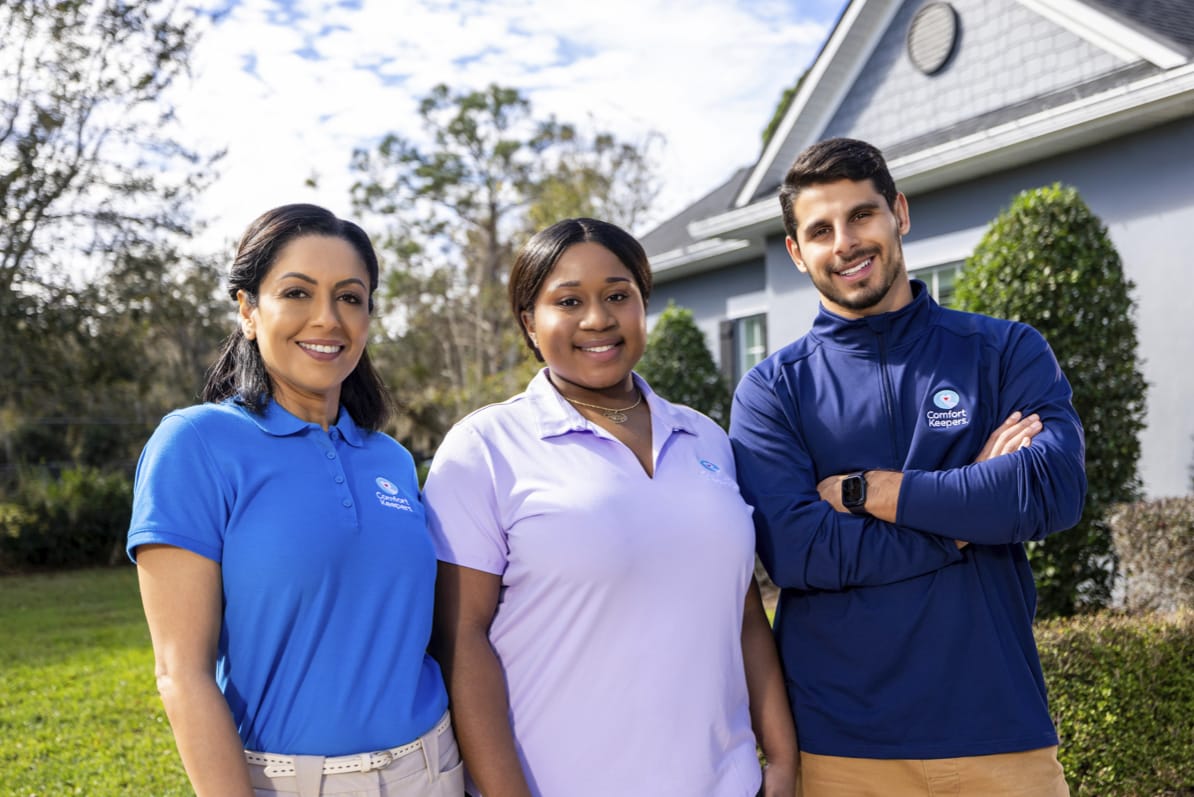 Three caregivers smiling outdoors at the facility