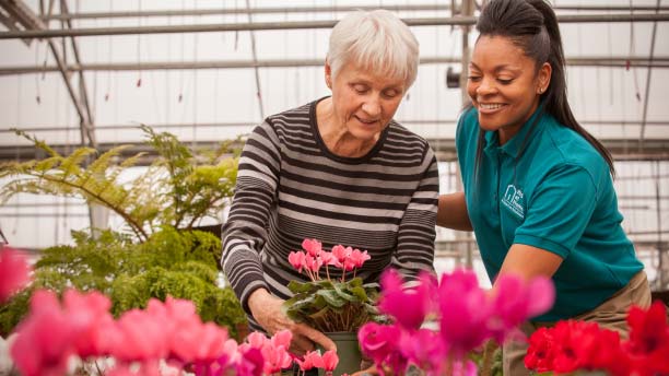 Senior resident gardening with staff assistance.