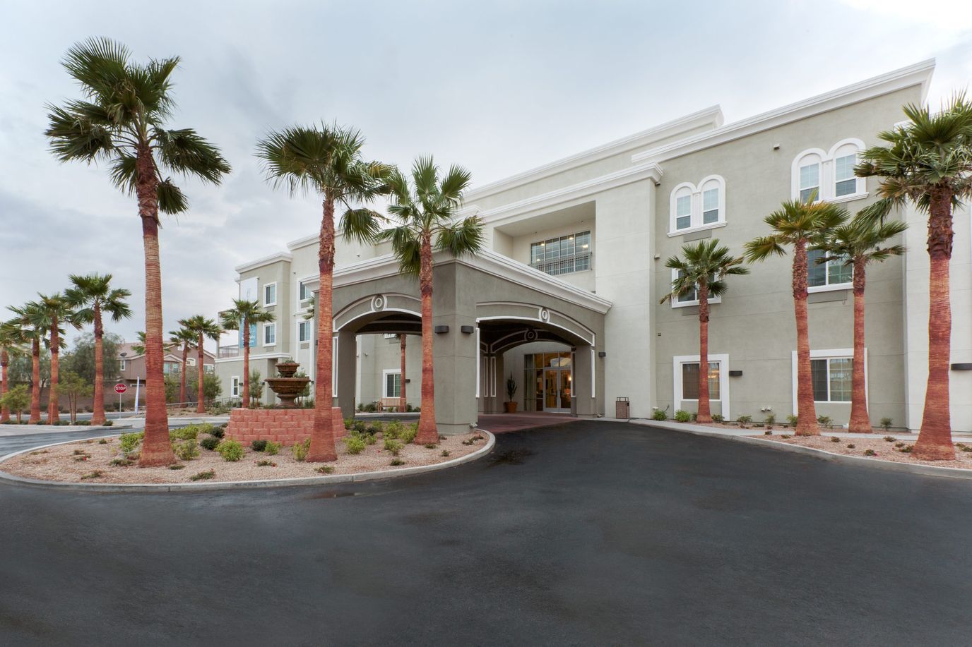 Exterior view of a senior living facility with palm trees