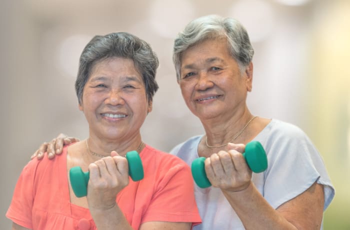 Two seniors exercising with dumbbells indoors