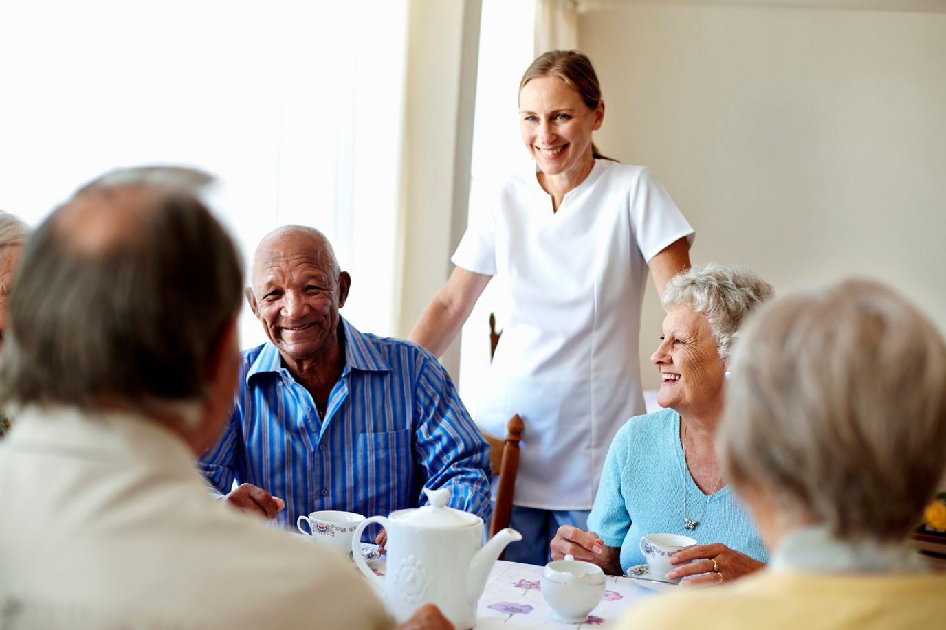 Residents enjoying tea with a caregiver in a dining area