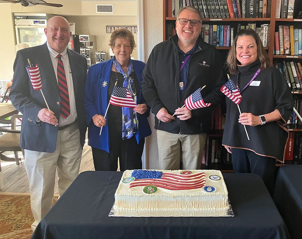 Staff celebrating a milestone with a cake and flags