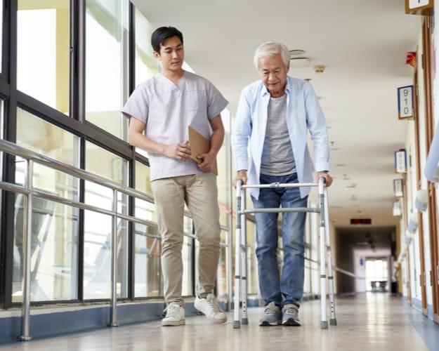 A staff member assists a senior resident in a hallway