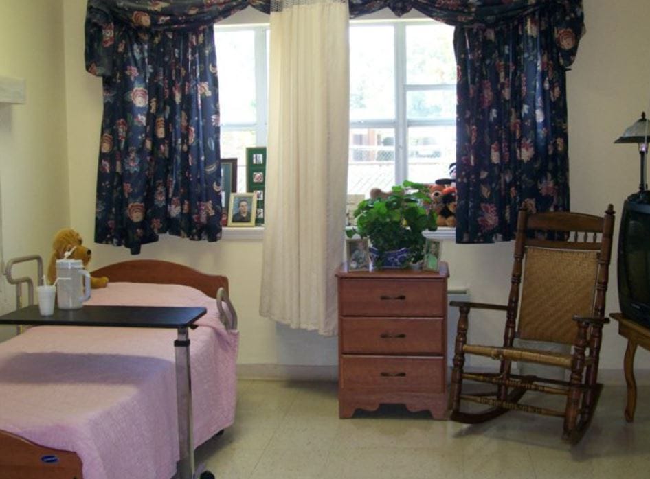 A cozy resident room with a bed and rocking chair