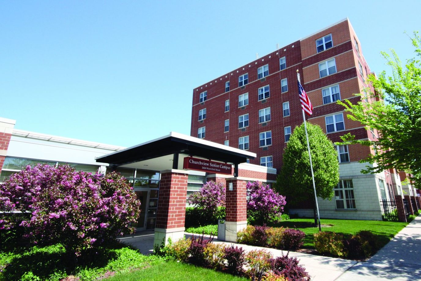 Entrance of Churchview Supportive Living with flowers and flag