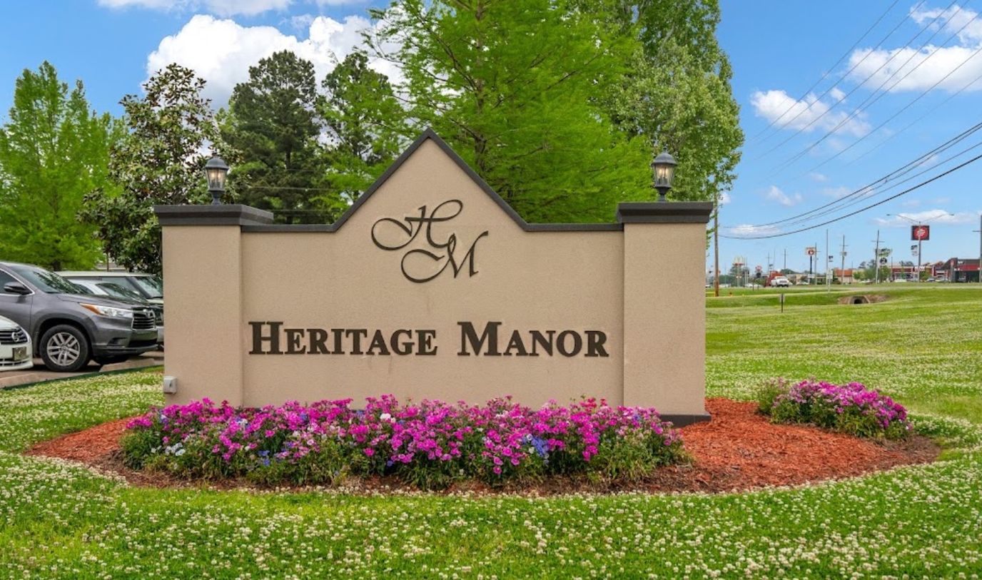 Sign of Heritage Manor surrounded by flowers