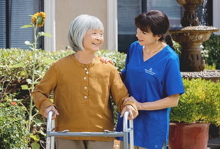 A caregiver assisting a senior woman outdoors
