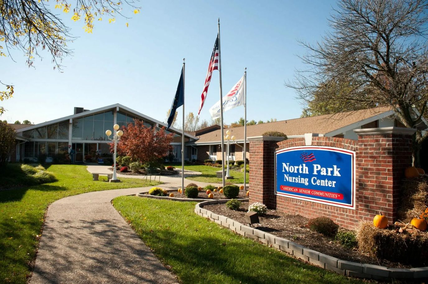 Exterior view of North Park Nursing Center with flags and pathway