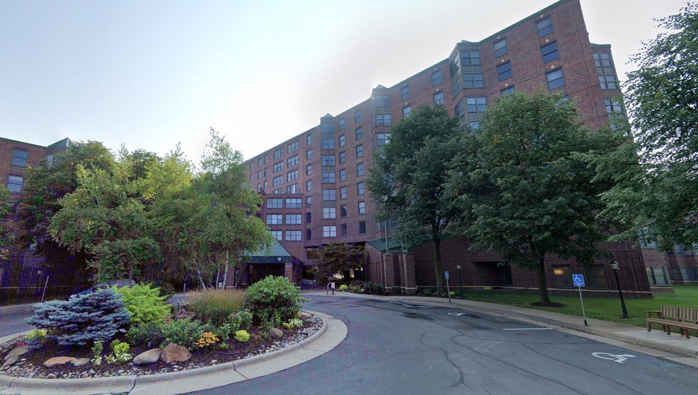 Entrance of a senior living facility surrounded by greenery