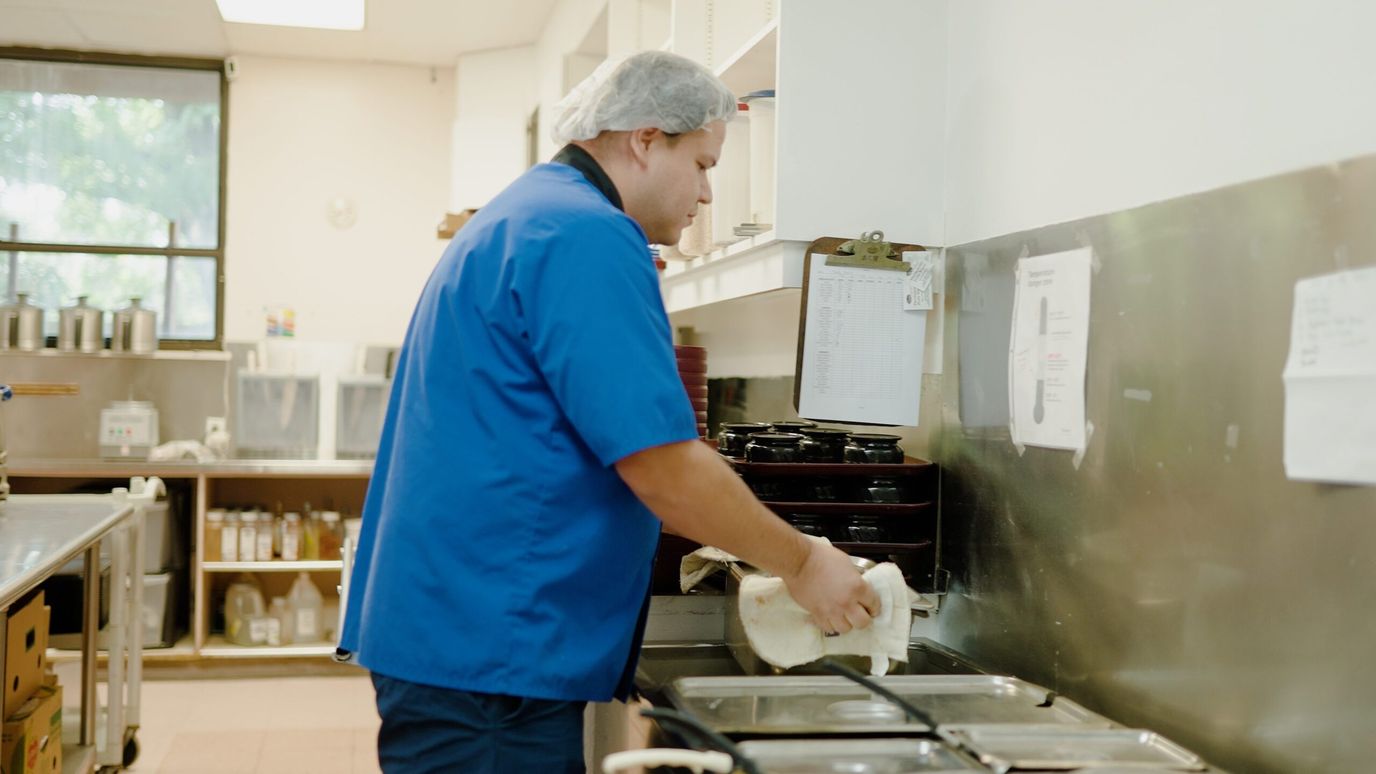 Windcrest Health and Rehabilitation, Nursing Home in Springdale, AR — Staff member preparing food in a kitchen