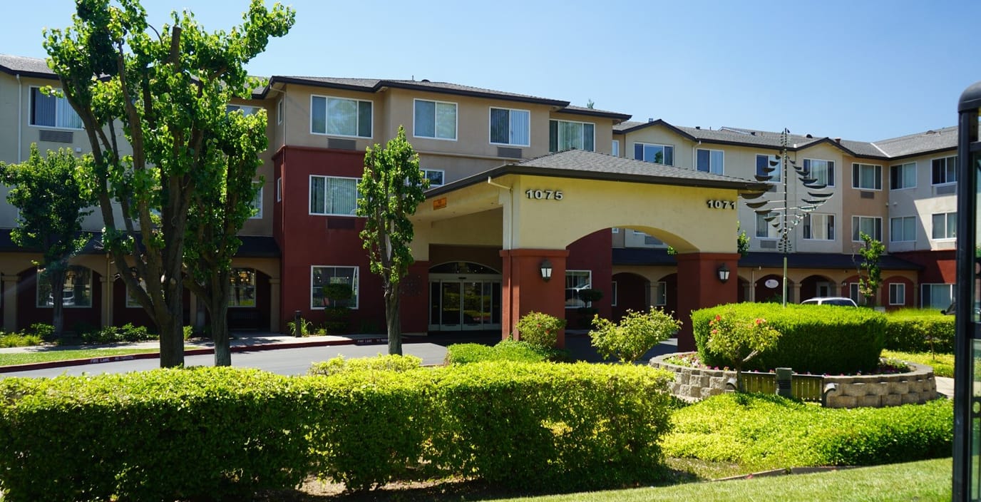 Front view of a senior living facility with gardens