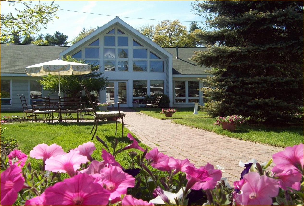 Exterior view of a senior living facility with flowers and seating area
