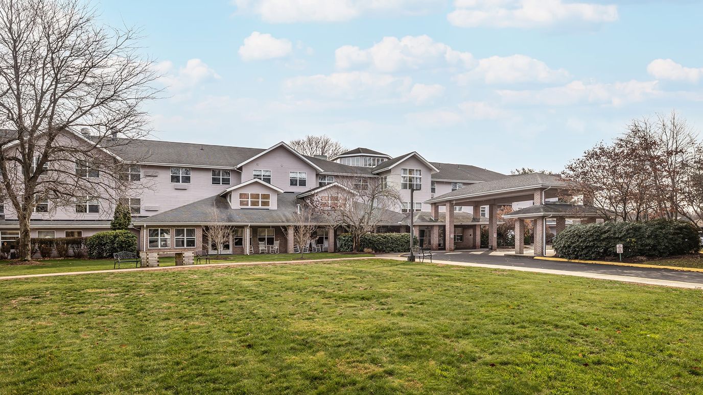 Exterior view of a senior living facility with a green lawn