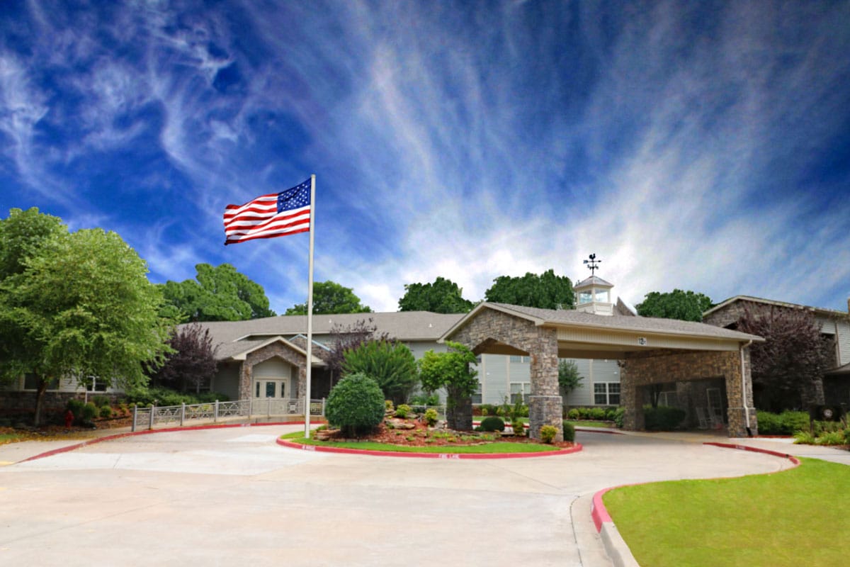 Exterior view of a retirement living facility with flag and gardens