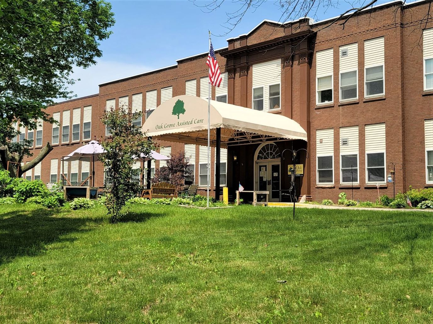 Entrance of Oak Grove Assisted Care with awning and greenery