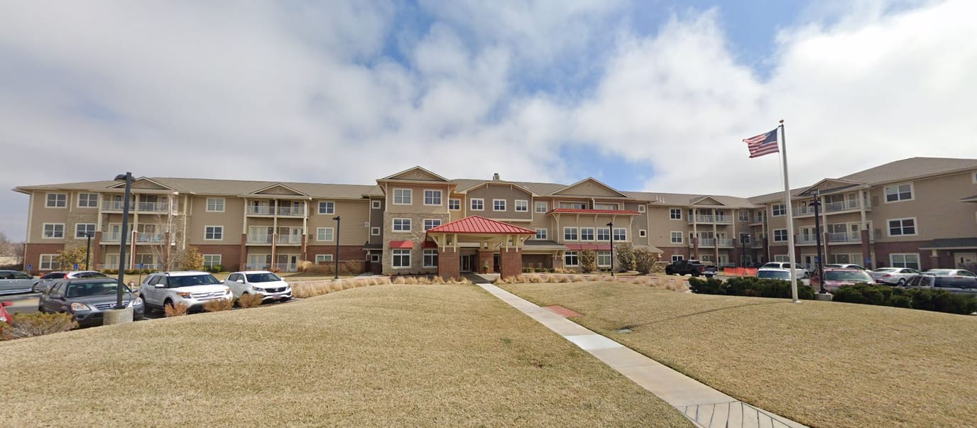 Exterior view of a senior living facility with flag and entrance