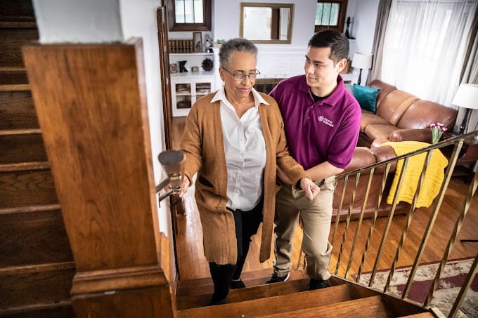 Staff assisting a resident up the stairs in a living space