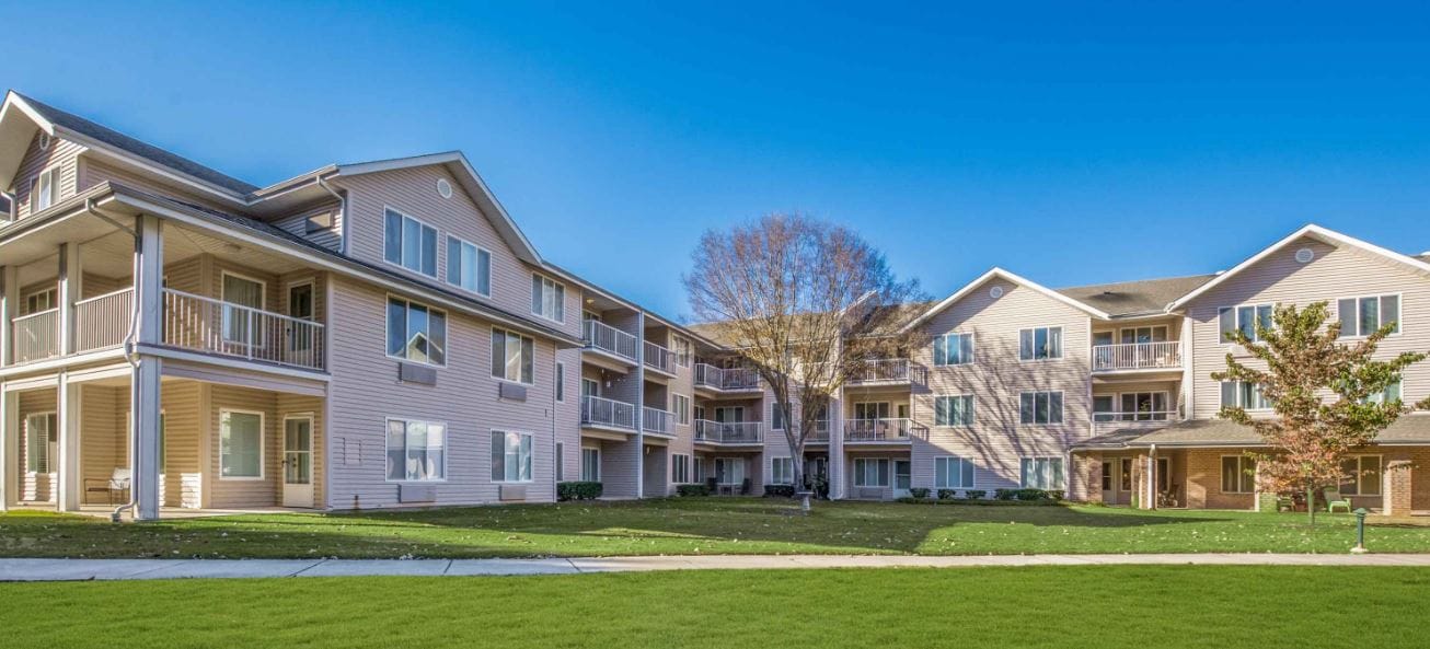 Exterior view of a senior living facility with green lawn
