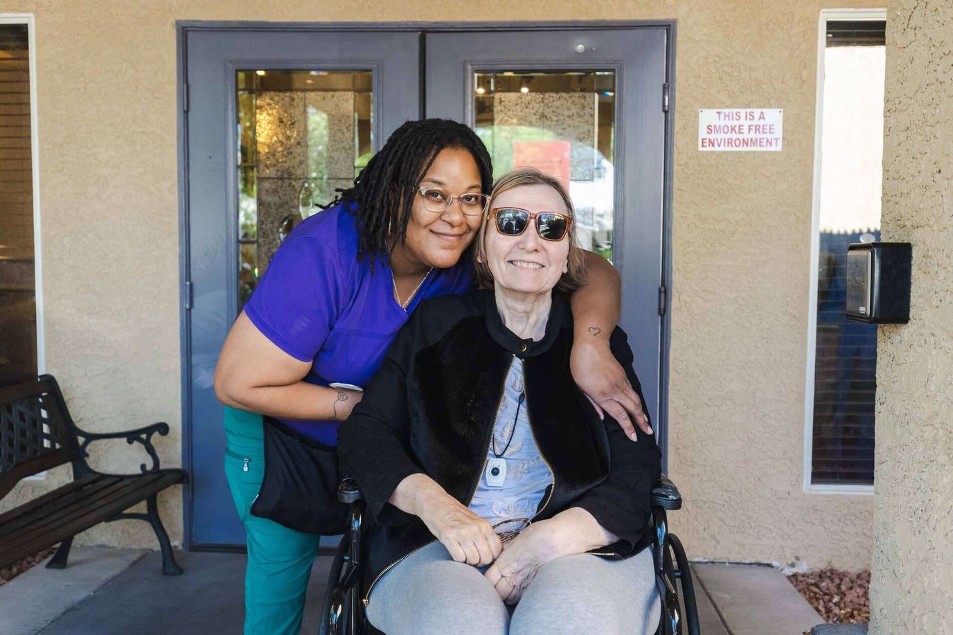 Staff member with a resident outdoors in front of the facility
