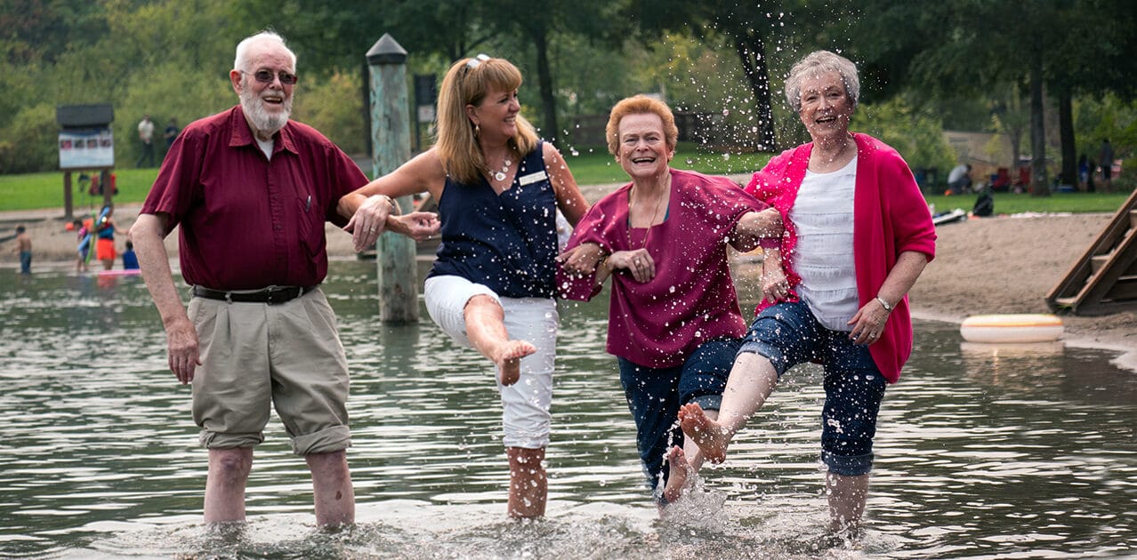 Four seniors enjoying splashing water together.