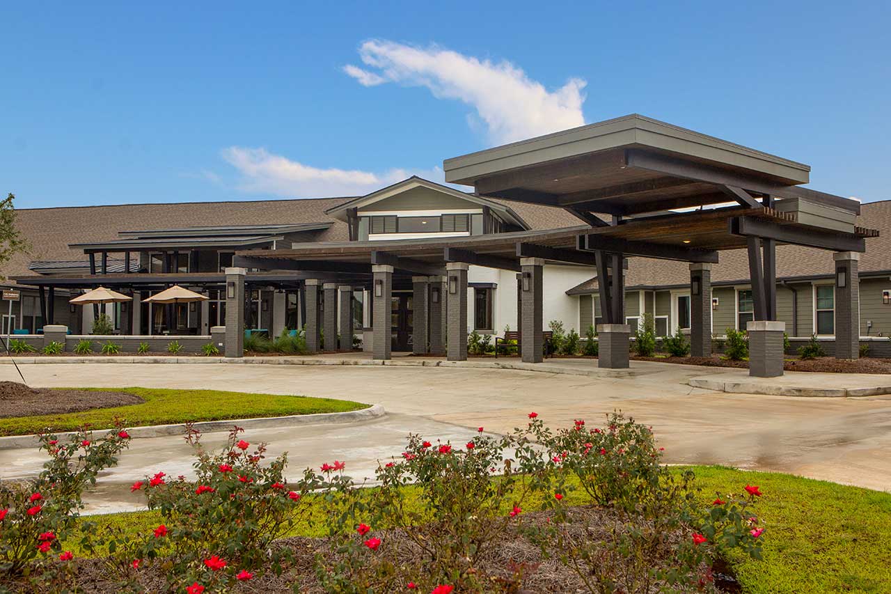Entrance of a senior living facility surrounded by landscaping