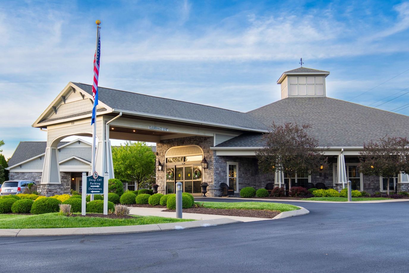 Exterior view of the senior living facility with landscaping and flag