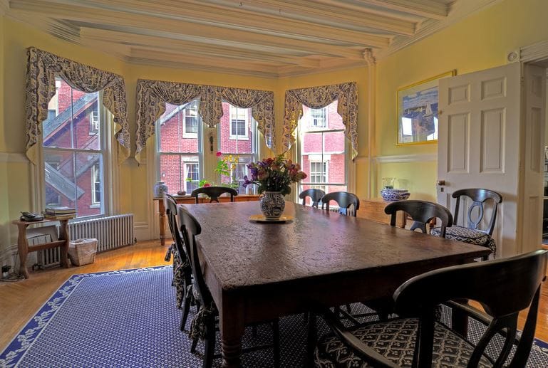 A bright dining room with large windows and a wooden table