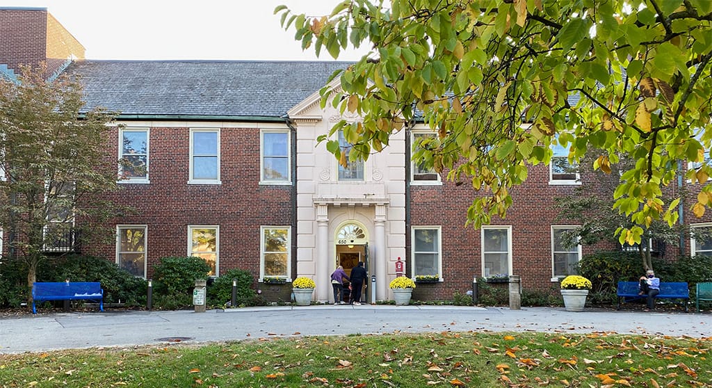 Front entrance of Neville Place Assisted Living with residents outside