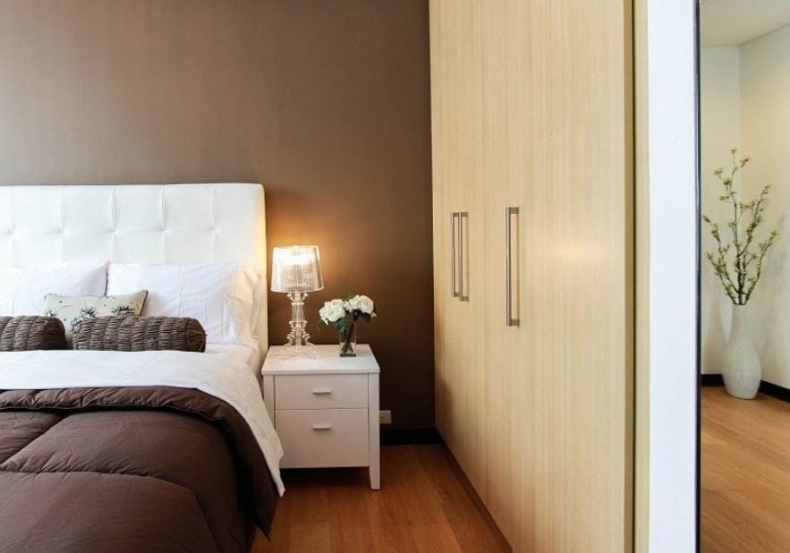 Well-appointed bedroom with a white bed, nightstand, and closet.