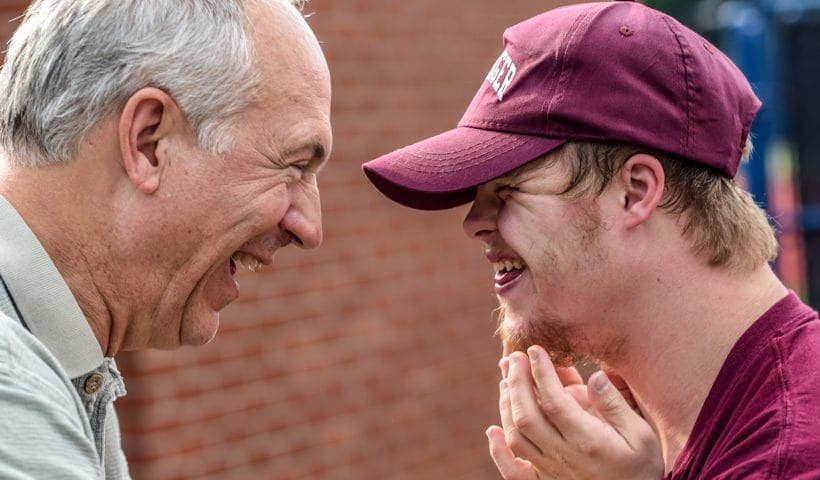 Two men laughing together outdoors.