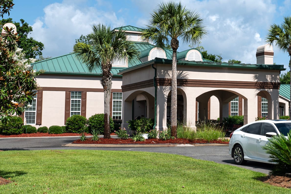 Exterior view of Magnolia Manor with palm trees and green roof
