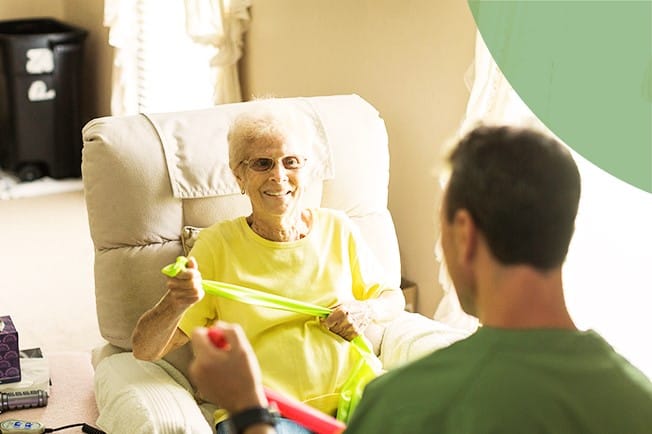 An elderly woman exercising with a therapist indoors