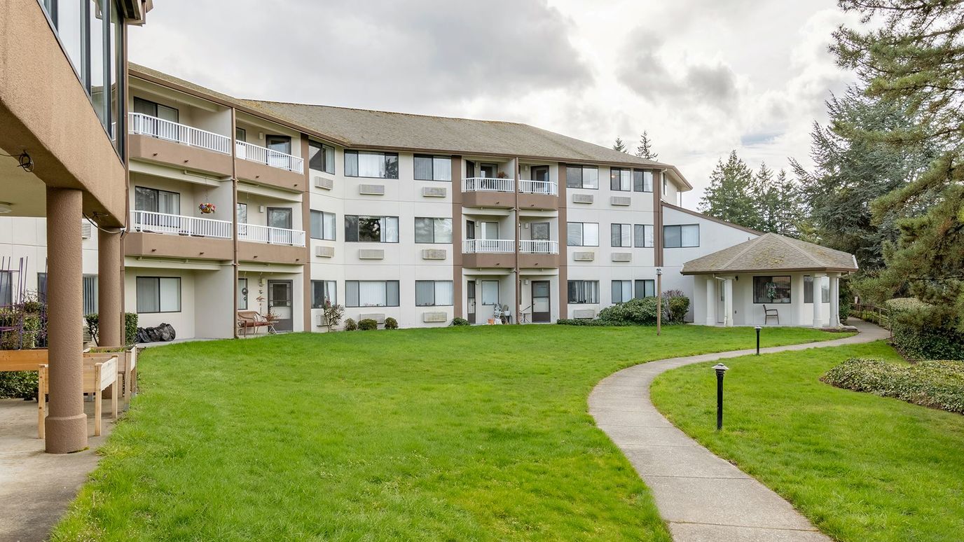 Exterior view of a senior living facility with gardens